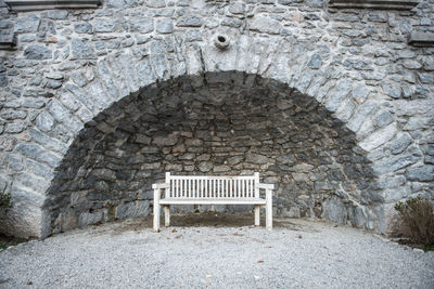 Empty bench against brick wall