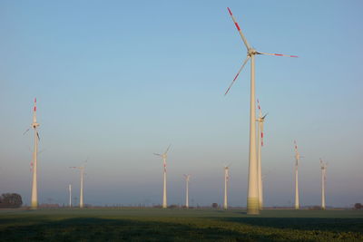 Low angle view of windmills on field against clear sky