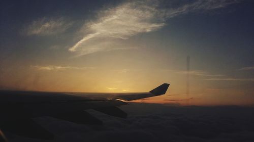 Airplane flying in sky at sunset