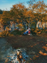 People sitting on street amidst trees during autumn