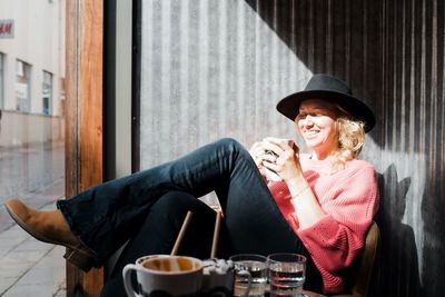 Woman sat laughing whilst in a cafe drinking coffee in the sun