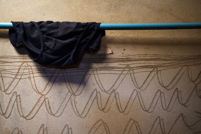 Close-up of panty drying on rod against wall