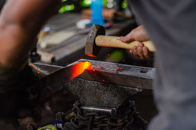 A blacksmith is hammering the hot red colour steel to make a knife