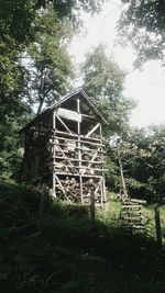 Abandoned built structure on field against trees in forest