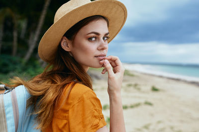 Portrait of beautiful young woman wearing hat at beach