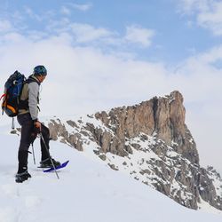 Full length of man hiking on snowcapped mountain against sky