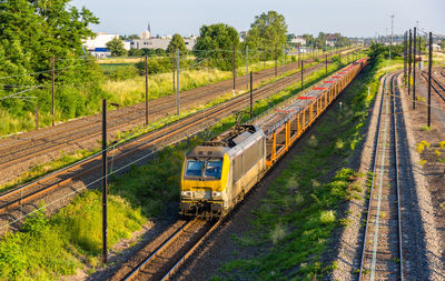 Train on railroad track amidst field against sky