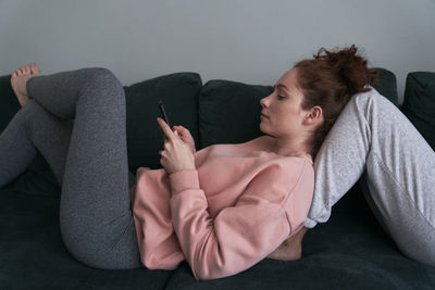 Young woman using phone on sofa at home