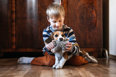 Boy with dog sitting on wooden floor