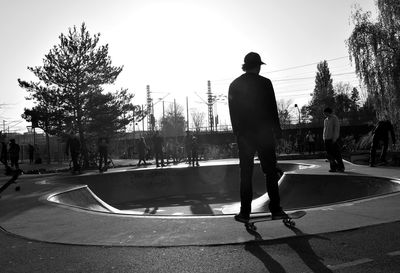 Rear view of man skateboarding on skateboard against sky