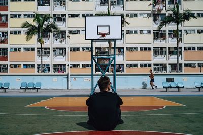 Rear view of man sitting on basketball court