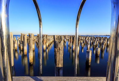 Panoramic view of wooden posts in sea against clear blue sky