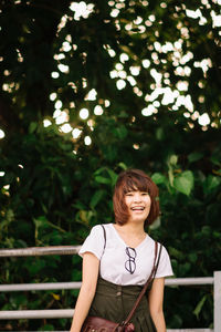 Young woman standing against trees