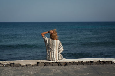 Rear view of man standing on sea against clear sky