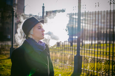 Young woman smoking while standing at park