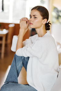 Portrait of young woman sitting on sofa at home