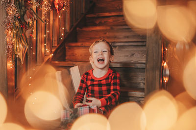 Portrait of cute girl standing by illuminated string lights