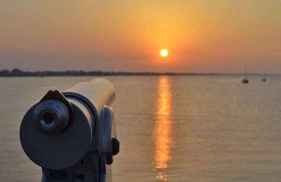 Close-up of camera on beach against sky during sunset