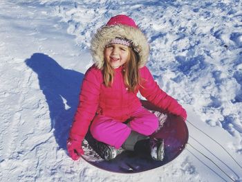 Happy girl sitting on sled in snow