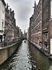 Canal amidst buildings in city against sky