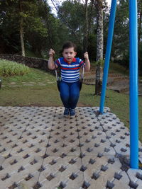 Full length portrait of boy swinging at park