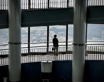 Rear view of woman standing by railing