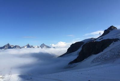 Scenic view of snowcapped mountains against blue sky