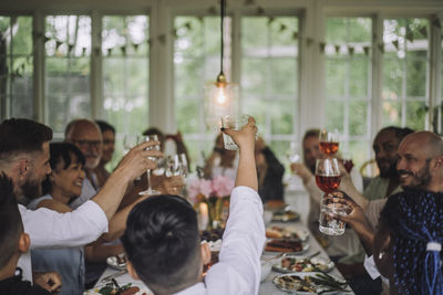 Multi-generation family toasting drinks during dinner party at home