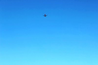 Low angle view of airplane against clear blue sky