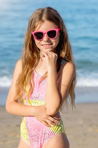 Fashion cute young girl posing on the beach in a summer swimsuit. 