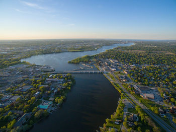 Aerial view of river amidst cities against blue sky during sunset