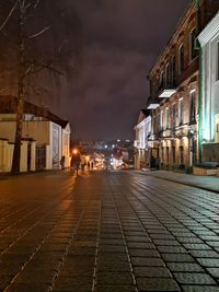 People on street amidst buildings in city at night