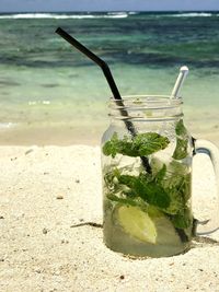 Close-up of drink on beach against sea