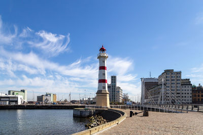 Lighthouse by sea against sky