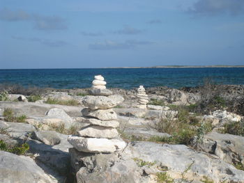 Rocks in sea against cloudy sky