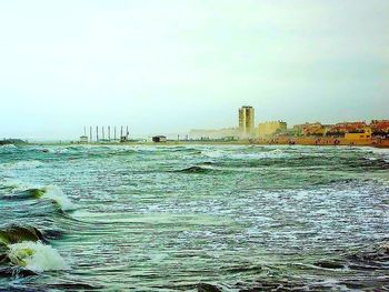 Scenic view of sea by buildings against sky