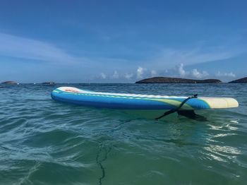 Paddleboard in sea against blue sky