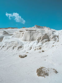 Scenic view of rocks by sea against blue sky