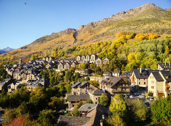 Scenic view of townscape and mountains against clear sky