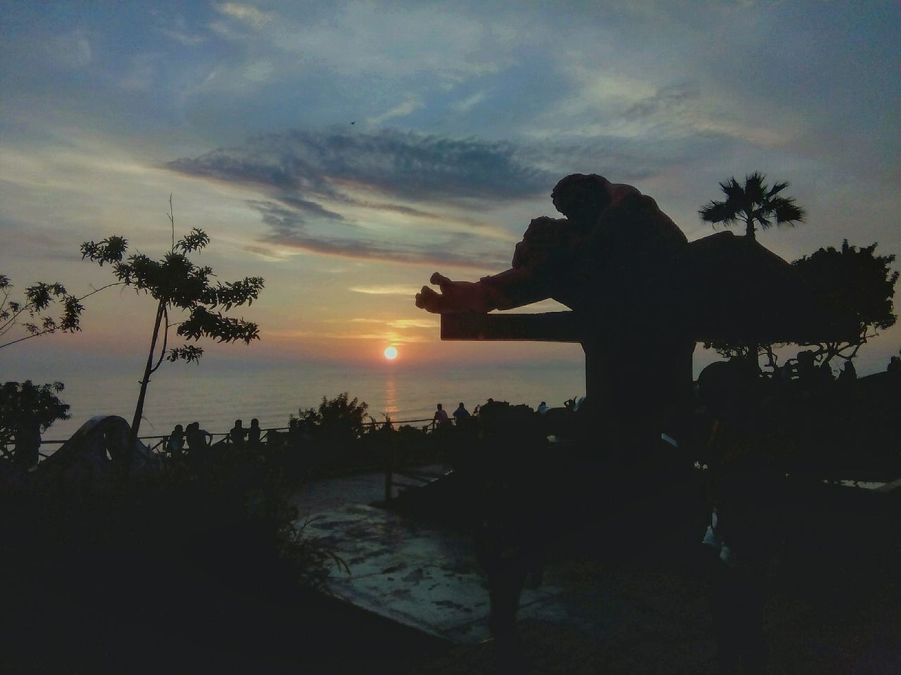 SILHOUETTE WOMAN PHOTOGRAPHING SEA AT SUNSET