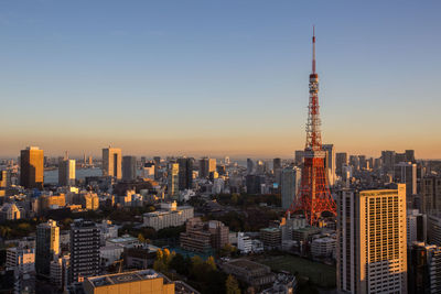 Tokyo tower and buildings in city against clear sky during sunset