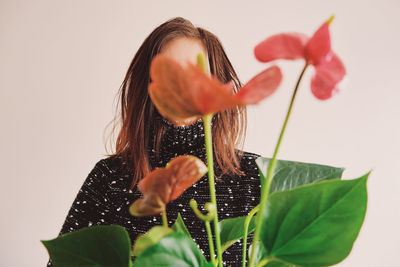 Woman holding pink flower against white background