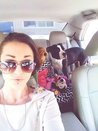 Portrait of young woman with dog in car