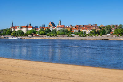 View of buildings by sea against clear blue sky