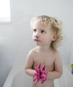 Girl looking up while standing in bathtub