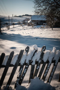 Snow covered fence against sky during winter