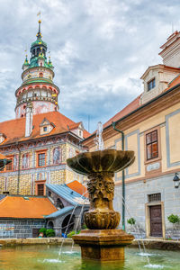 Fountain by building against sky