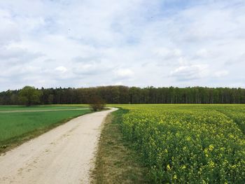 View of field against cloudy sky