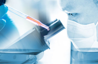 Close-up of scientist looking through microscope