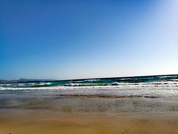 Scenic view of beach against clear blue sky